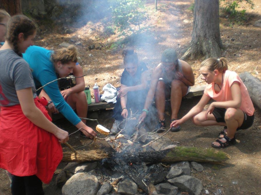 Group of girls sitting around a campfire at summer camp