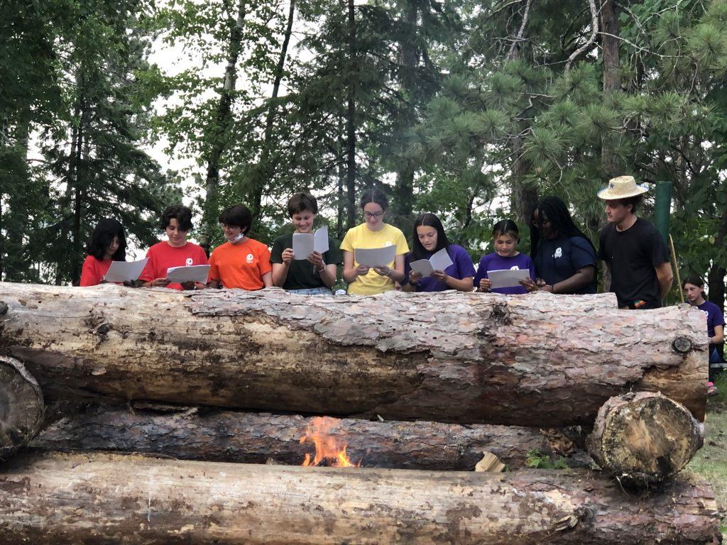 A group of happy families gathered around a campfire at Camp Kamaji, experiencing the joy and growth that comes with the question of why families love Camp Kamaji